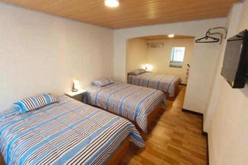 a hotel room with two beds and a flat screen tv at Casa San Andres Hostal in Pasto