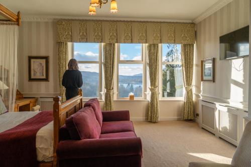 a woman standing in a bedroom looking out the window at Merewood Country House Hotel in Windermere