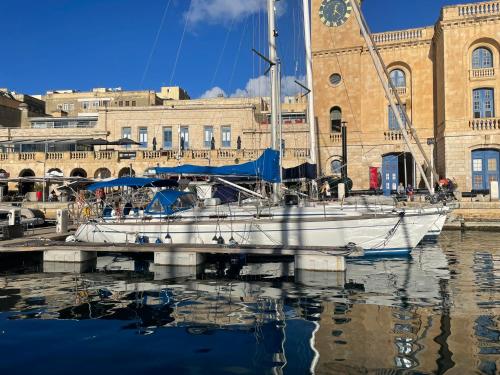 a white boat docked at a dock with a clock tower at Entire boat 3 cabins in Birgu vittoriosa in Birgu