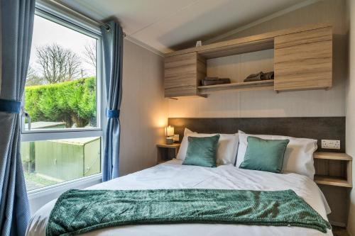 a bedroom with a bed and a large window at Finest Retreats - Pine Forest Lodge in Saint Enoder
