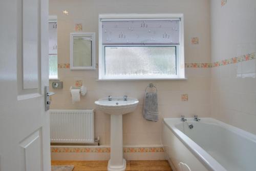 a bathroom with a sink and a tub and a window at 3 Bed in Sennen Cove oc-p00781 in Sennen