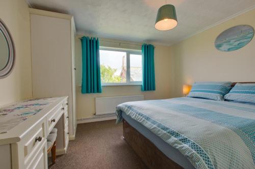 a bedroom with a bed and a window with blue curtains at 3 Bed in Sennen Cove oc-p00781 in Sennen
