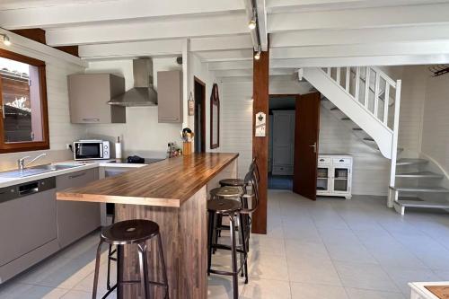 a kitchen with a wooden counter and stools in it at chalet with swimming pool in leisure park in Gujan-Mestras