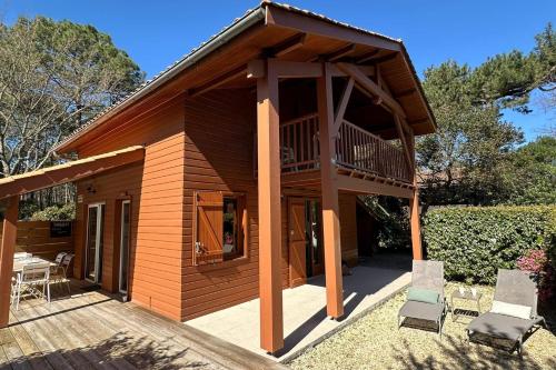 a wooden cabin with a deck and two chairs at chalet with swimming pool in leisure park in Gujan-Mestras