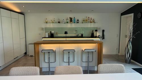a kitchen with a bar with four stools at Exklusives Architektenhaus, Pool und Privateinfahrt in Mönchengladbach