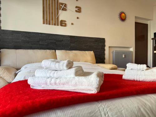 a bed with white towels on a red blanket at Nido Alpino - casetta con giardino, vista montagne in Tirano