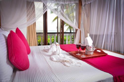 a bed with a tray of towels and two glasses of wine at Sunset Fort Galle in Galle
