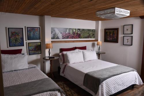 a bedroom with two beds and paintings on the wall at La Estancia Hotel Boutique in Salamina