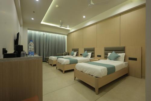 a hotel room with three beds and a television at Sarju Palace in Valsād