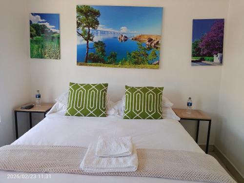 a bedroom with a white bed with three paintings on the wall at Alikho luxury accommodation in Abisai