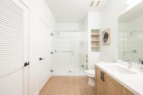 a white bathroom with a shower and a toilet at The Village Collection with Gym Pool and Spa in Montclair