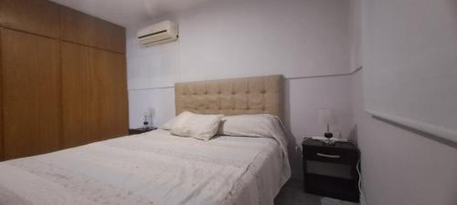 a bedroom with a white bed and a wooden cabinet at Depto 75m 2 dormitorios Frente al Parque Central con Cochera en el Centro denMendoza in Mendoza
