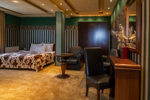 a bedroom with a bed and a chair and a table at Garni Hotel Garson-Lux NS in Novi Sad
