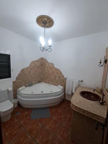 a bathroom with a tub and a toilet and a sink at Jaye’s Home in Arona