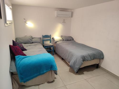 Un dormitorio con dos camas y una silla. en RDC a 2 pas du port, en Port-Vendres