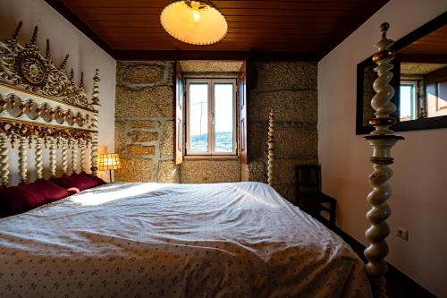 a bedroom with a bed with a white comforter and a window at Casa do Miradouro in Guarda