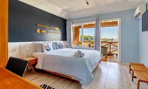a bedroom with a large white bed and a balcony at Pousada Santorini in Búzios