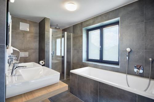 a bathroom with a tub and a sink and a window at Kristall Plaza in Niederau