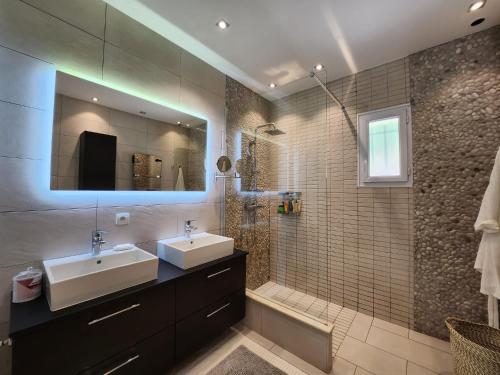 a bathroom with two sinks and a shower with a mirror at happyfew villa laghet in La Trinité