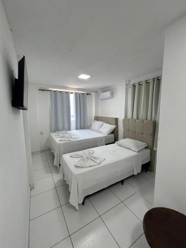 a bedroom with two beds and a flat screen tv at Pousada Avenida MELHOR CUSTO-BENEFÍCIO in Teixeira de Freitas