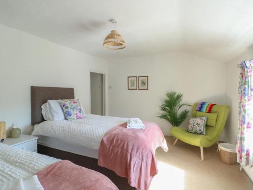 a bedroom with a bed and a green chair at Castle Gardens Apartment in Beaumaris