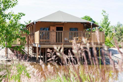 a wooden house with a porch and a roof at Vakantiepark Sallandshoeve in Nieuw-Heeten