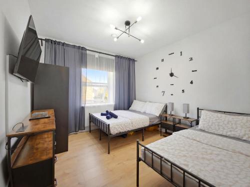 a bedroom with two beds and a tv and a couch at Urban retreat near the station in London