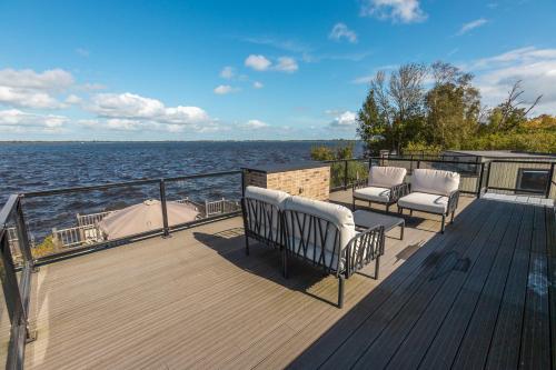 a deck with two chairs and a boat on the water at Vakantiepark De Wiedense Meren in Wanneperveen