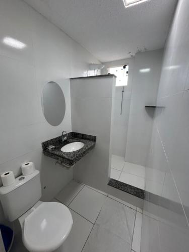 a white bathroom with a toilet and a shower at Pousada Avenida MELHOR CUSTO-BENEFÍCIO in Teixeira de Freitas
