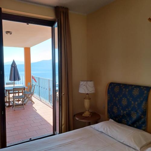a bedroom with a bed and a view of a balcony at Residence Il Vigneto - Casa Sopralago in Oggebbio