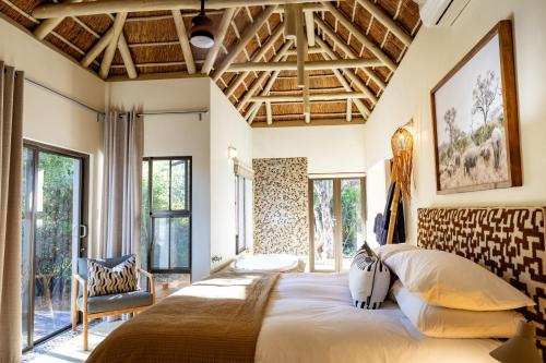a bedroom with a large bed and large windows at Villa Blaaskans in Hoedspruit
