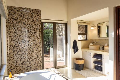 a bathroom with a shower with a glass door at Villa Blaaskans in Hoedspruit
