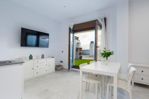 a white kitchen with a white table and chairs at Áticos Lux Sevilla Piscina Parking in Bormujos