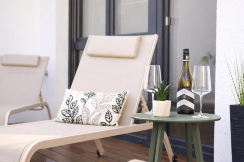 a white chair next to a table with a bottle of wine at Whirlpool & Terrasse - Familien & Gruppenfreundlich in Aschaffenburg