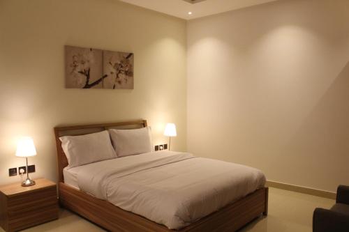 a bedroom with a bed and two lamps on tables at Nital Furnished Apartment in Riyadh