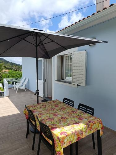 a patio with a table and an umbrella at Casa Azul (Blue House) in Urzelina