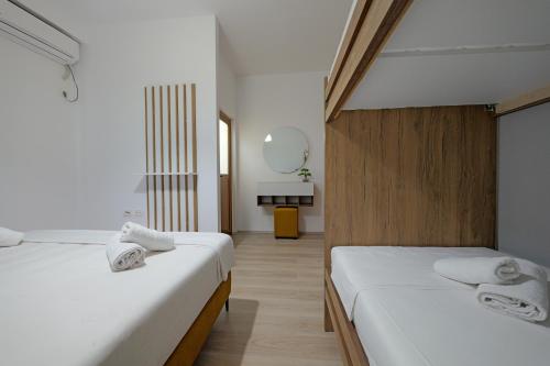 two beds in a room with white walls at Sunny Hotel in Sarandë