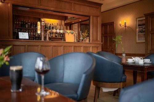 a restaurant with blue chairs and a bar at Cragwood Country House Hotel in Windermere