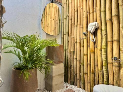 a bathroom with a bamboo wall with a toilet and two plants at Kalunay Hostel - Breakfast included in Puerto Viejo