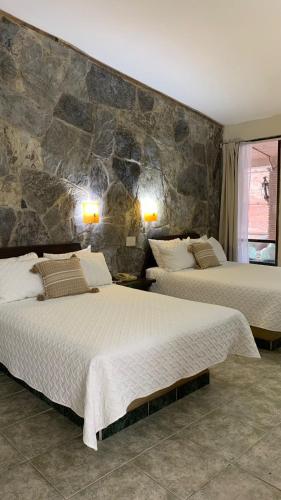 a bedroom with two beds and a stone wall at Hotel El Rancho in San Juan Bautista Tuxtepec