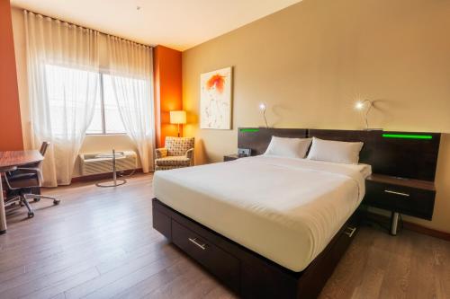 a bedroom with a large bed and a desk at Hôtel Must Aéroport de Québec par JARO in Quebec City