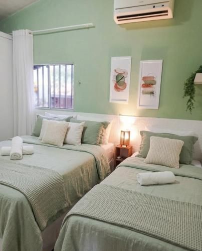 two beds in a room with green walls at Garden JP in João Pessoa