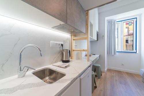 a kitchen with white counters and a sink and a window at Hygge Smart Stays in Lisbon