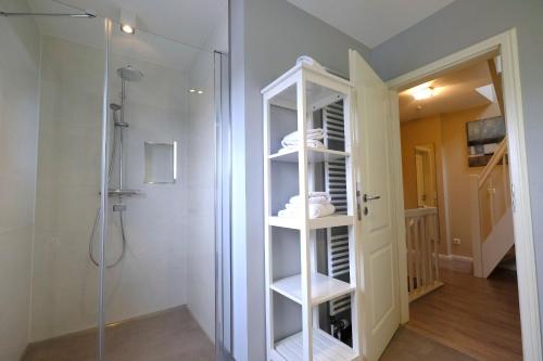 a bathroom with a shower and a white shelving unit at Friesenjung in Wenningstedt