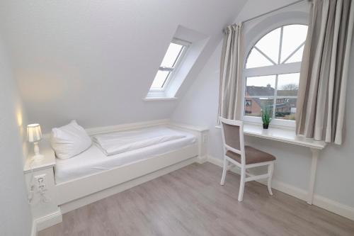 a white room with a window seat and a chair at Friesenjung in Wenningstedt