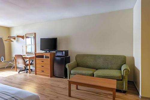 a living room with a green couch and a desk at Budget Inn in Ithaca