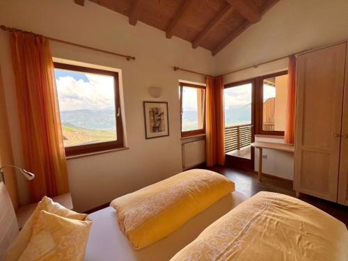 a bedroom with two beds and two windows at Schloss-Hof in Appiano sulla Strada del Vino