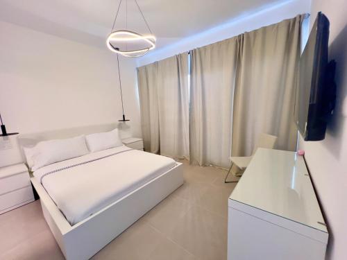 a white bedroom with a bed and a tv at Downtown Chic Donde inicia la diversión en Punta Cana in Punta Cana