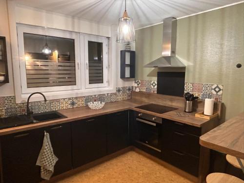 a kitchen with black cabinets and a sink and a window at Lestandardgravelines in Gravelines