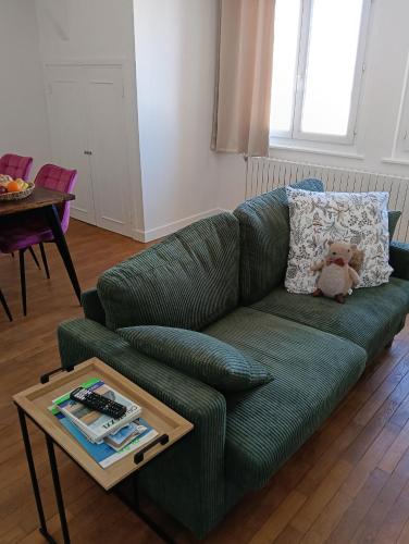 a green couch in a living room with a teddy bear on it at Le Refuge de la Tour in Calais
